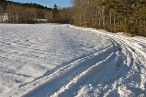 Snow-covered field with snowmobile trail.